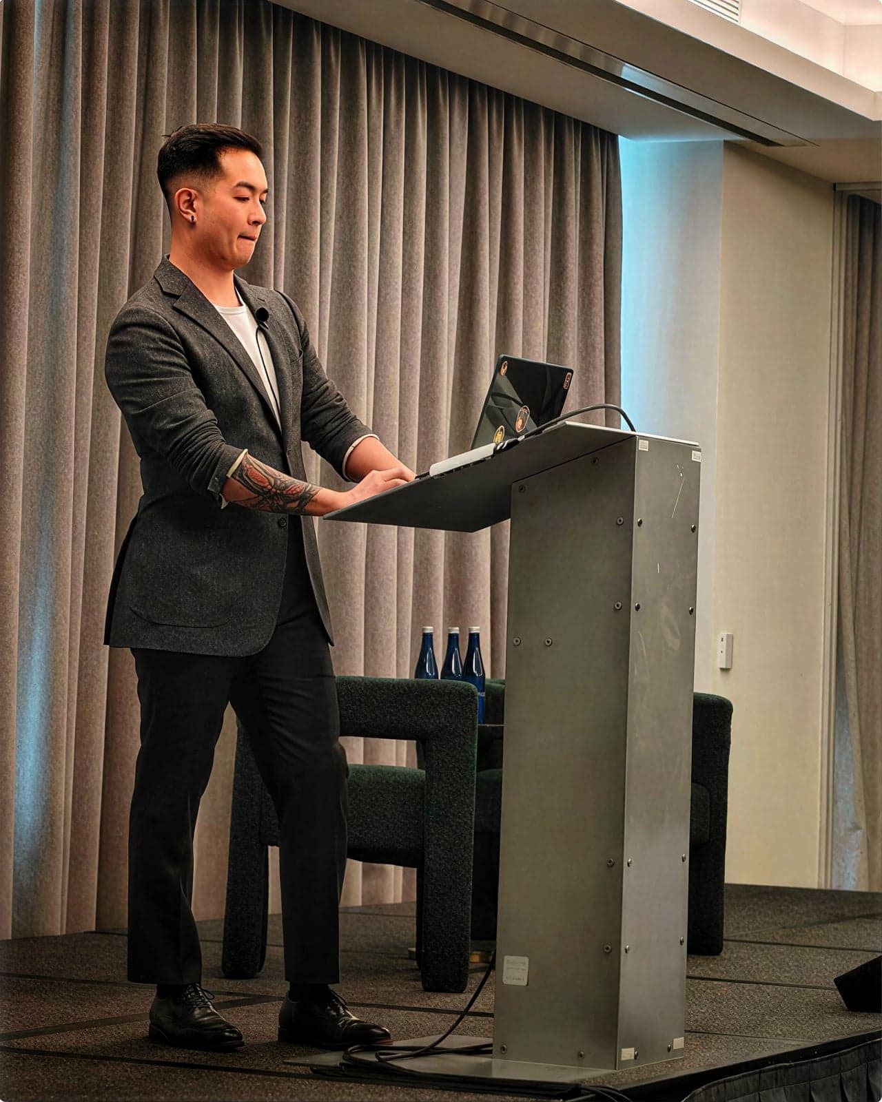 Alex Tong presenting at a lectern with his laptop.